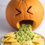 Close-up of a puking pumpkin with guacamole and tortilla chips
