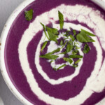 Overhead photo of red cabbage soup with a heavy cream swirl
