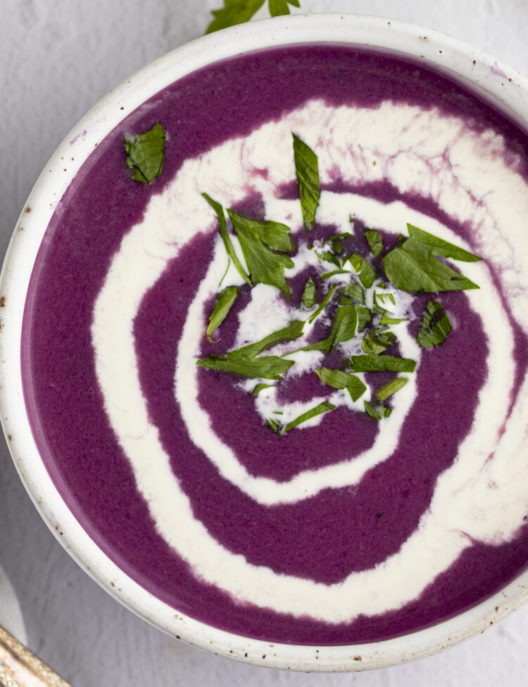 Overhead photo of red cabbage soup with a heavy cream swirl