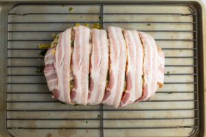 Uncooked bacon wrapped turkey breast on a baking rack
