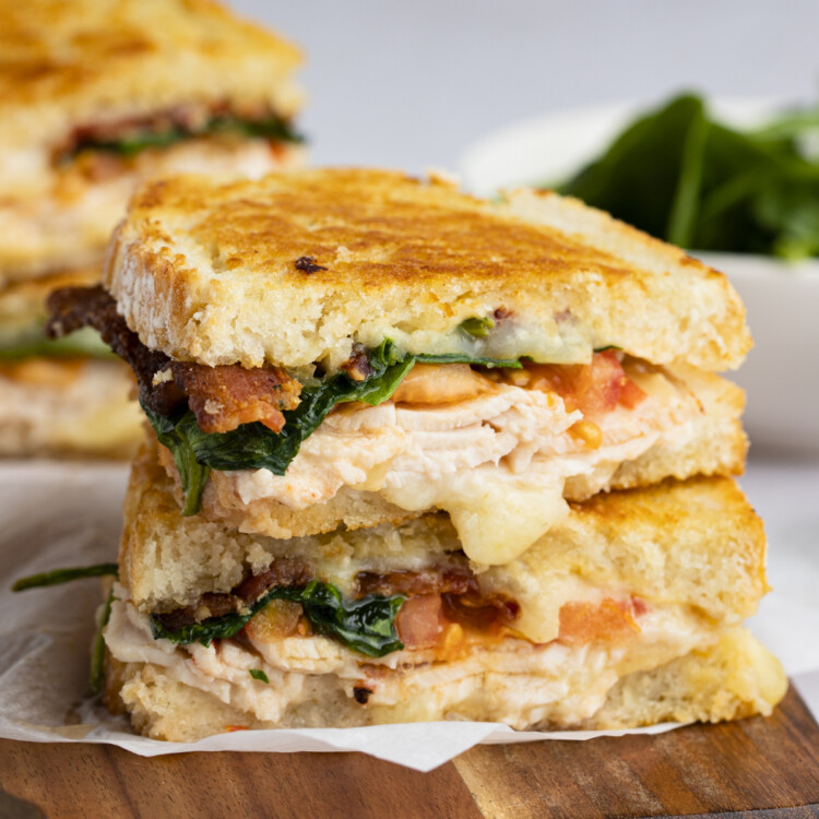 Two halves of a turkey melt stacked on top of each other, on a wooden tray