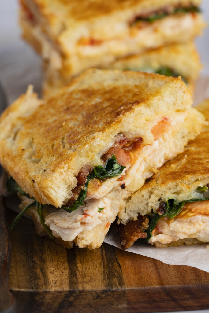 Two halves of a turkey melt, one leaning across the top of the other, on a wooden tray
