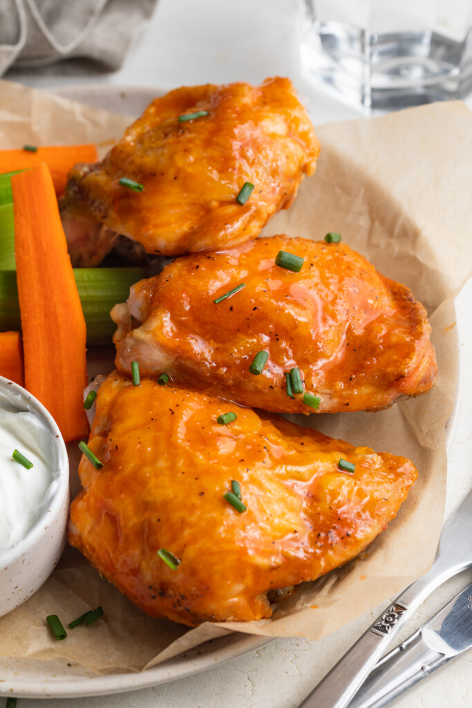 buffalo chicken thighs on a plate with carrots and celery on the side