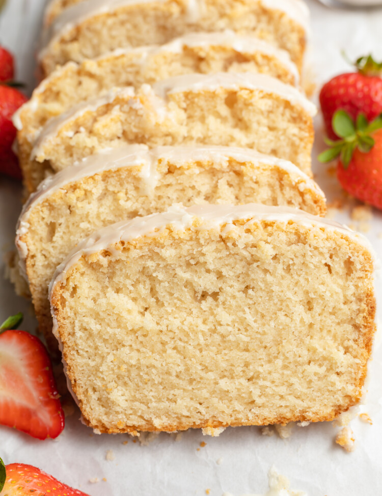 close up image of sliced vegan pound cake with strawberries on the side