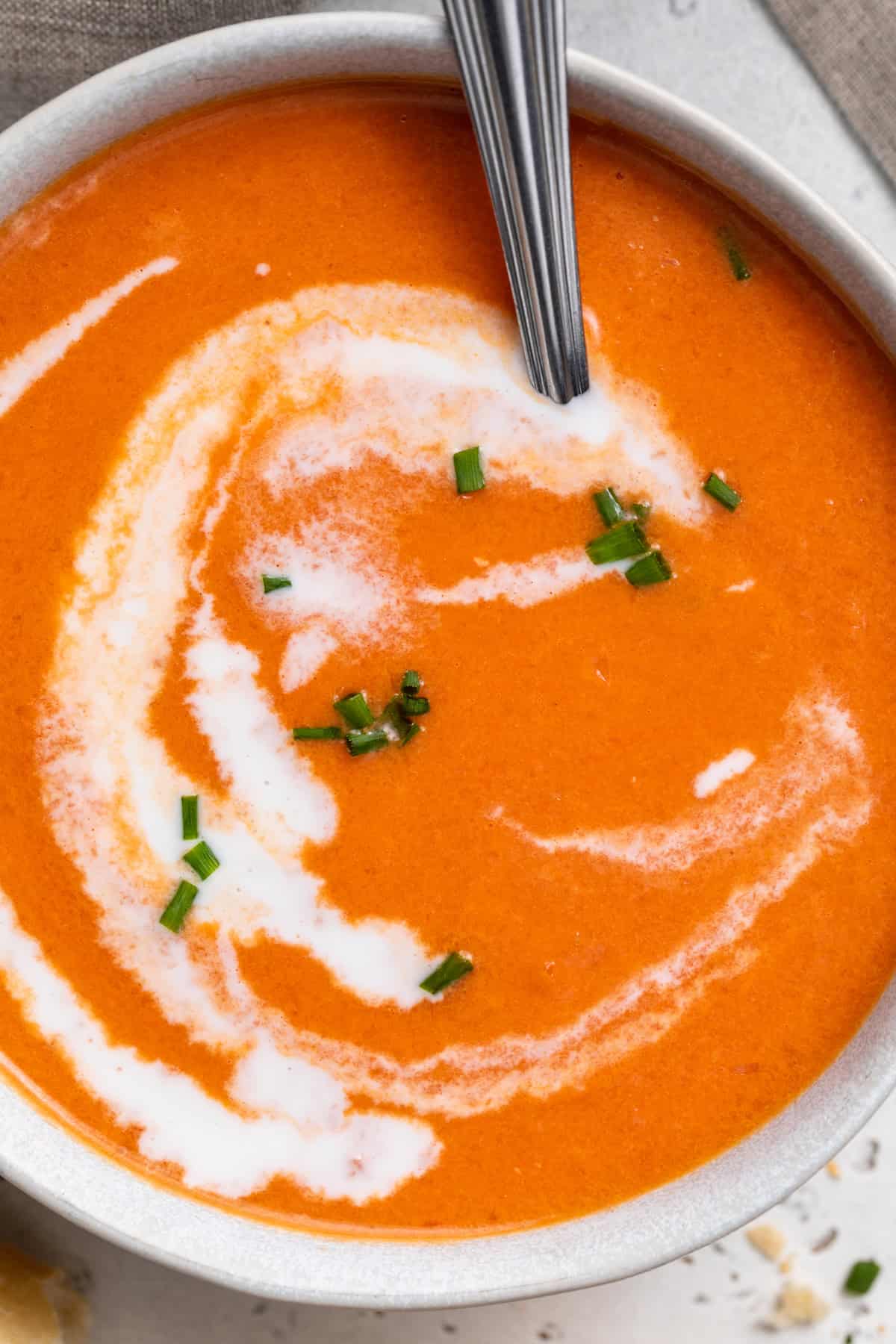 close-up overhead image of gluten-free tomato soup in a bowl with heavy cream swirled on top