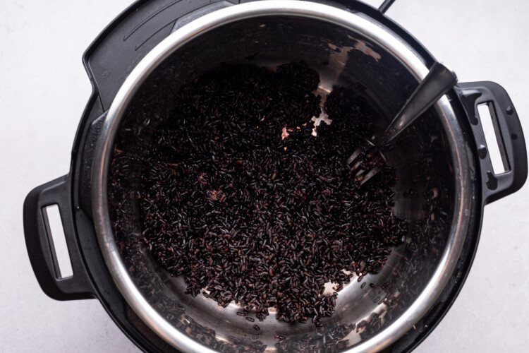Closeup view of black rice in Instant Pot on a white background.