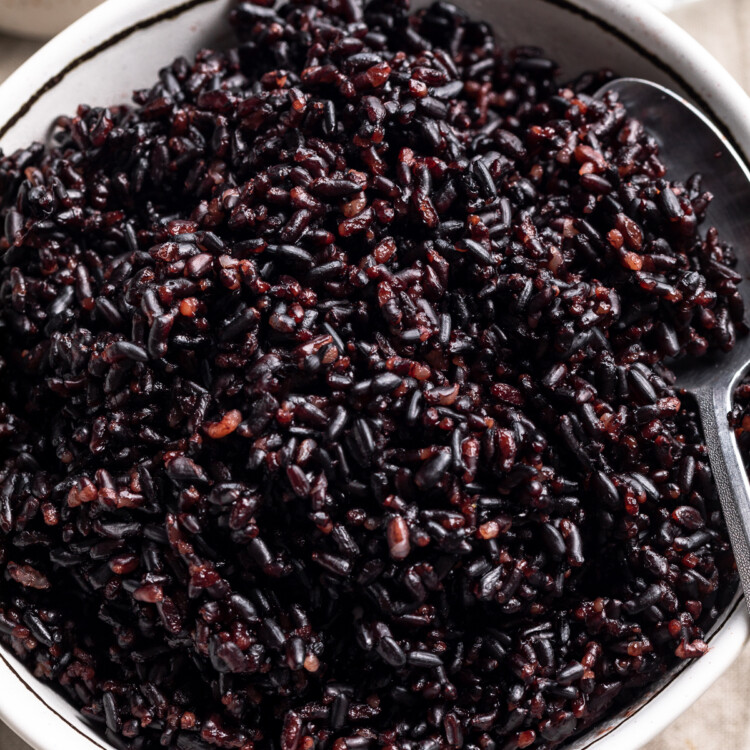 Overhead view of a white bowl of Instant Pot black rice on a white tablecloth.