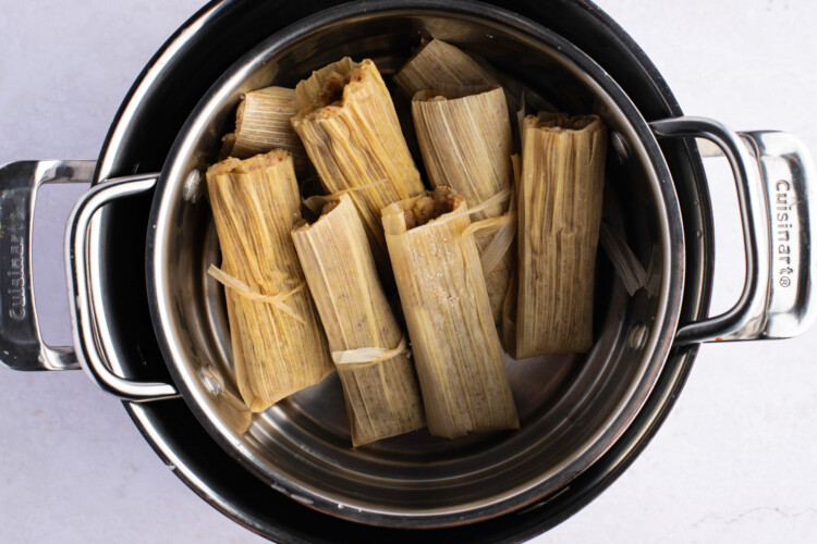 Keto tamales standing upright in steamer on white background.