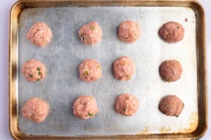 Overhead view of Asian turkey meatballs on a lightly greased baking sheet.