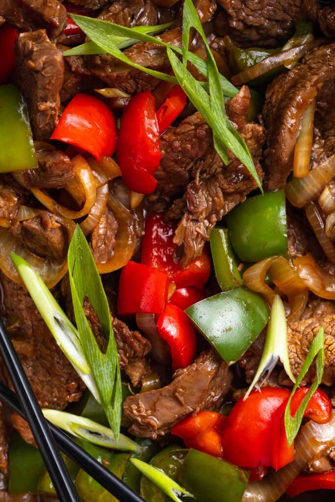Close-up photo of beef with oyster sauce and stir fry vegetables in a large silver bowl.