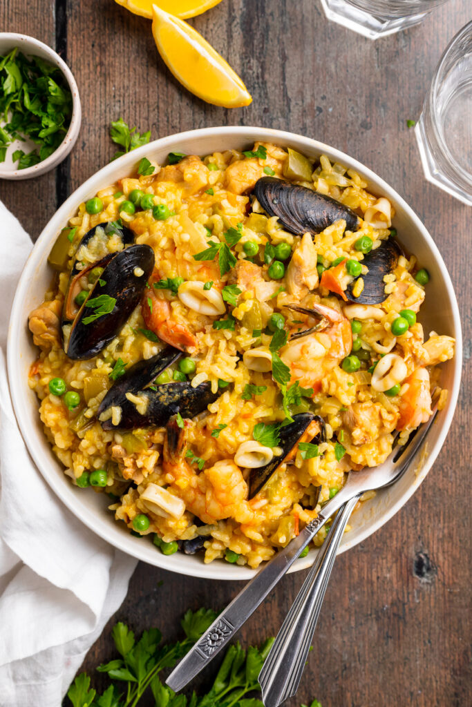Overhead view of a plate of Instant Pot paella on a wooden tabletop.