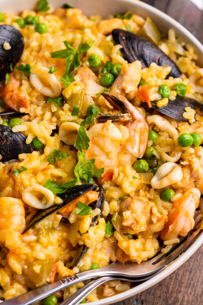 Close-up view of Instant Pot Paella on a large neutral round plate with a fork.