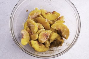 Large glass bowl of peaches, cinnamon, lemon juice, and erythritol for keto peach cobbler.