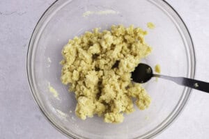 Keto cobbler crust dough in large glass mixing bowl with fork.