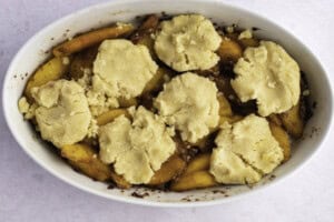 Keto peach cobbler in large white oval baking dish.