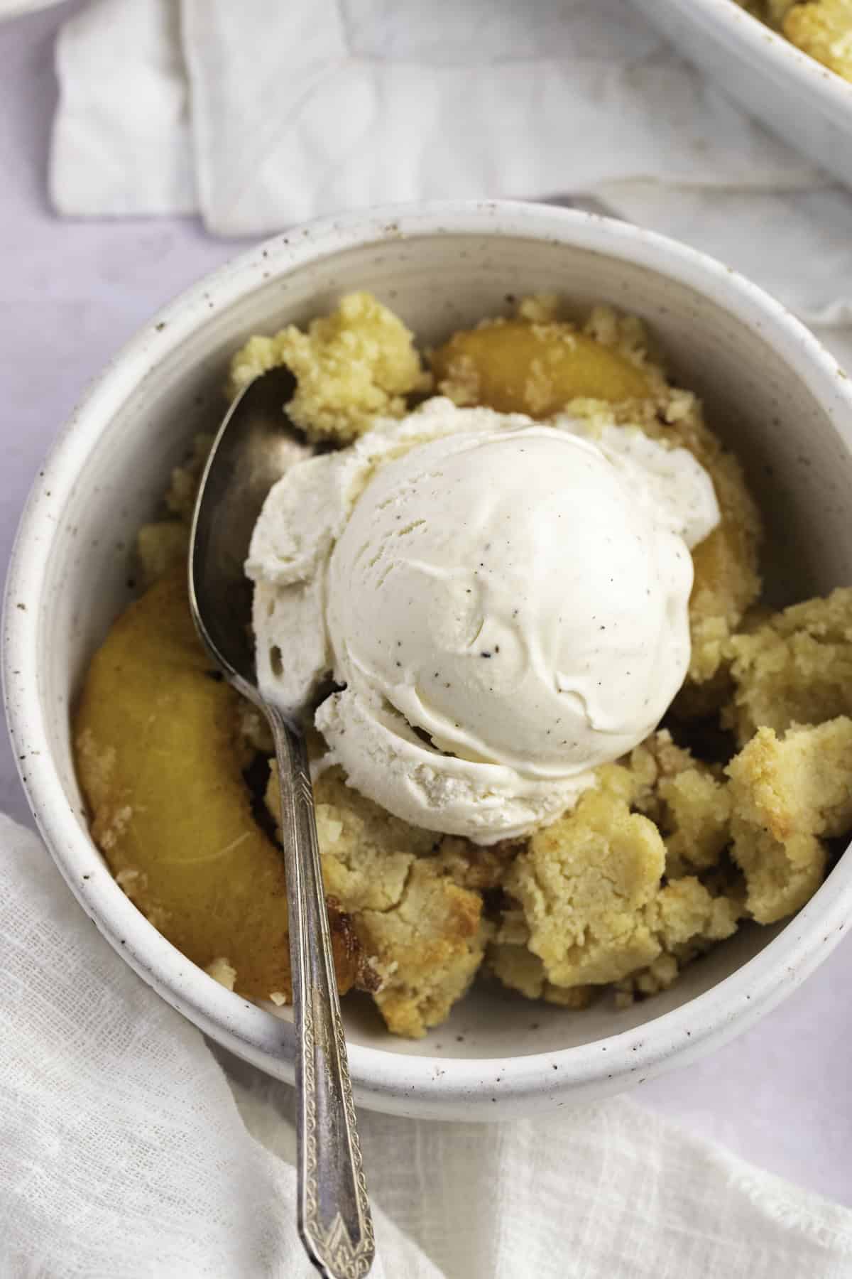 Overhead view of a bowl of keto peach cobbler with keto vanilla ice cream.