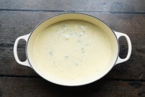 Overhead view of a large soup pot containing veggies and heavy cream for soup.