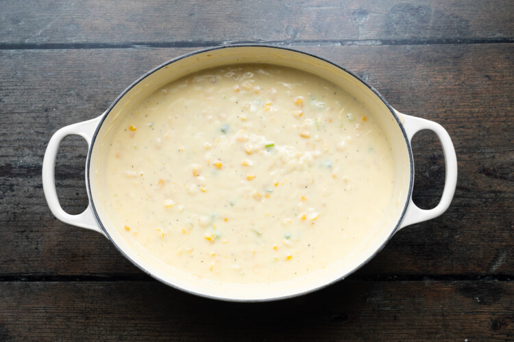 Overhead view of a large soup pot containing corn soup.
