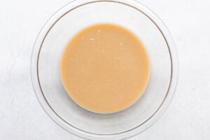 Butter, almond milk, white sugar, and brown sugar mixed together in large glass mixing bowl.
