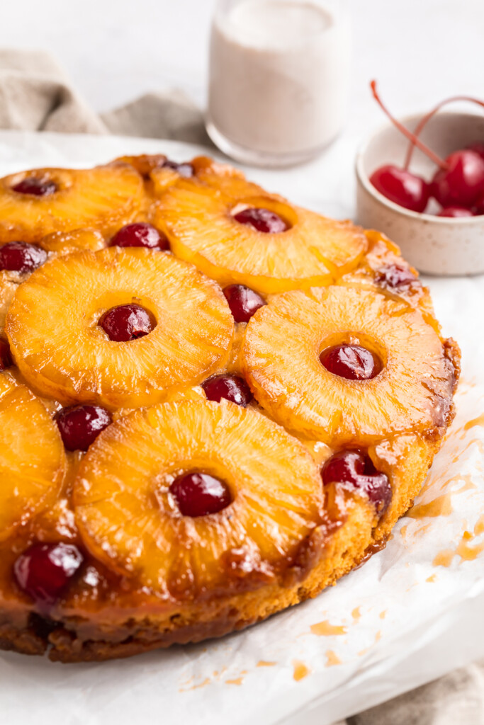 Close-up, 3/4 angle shot of a vegan pineapple upside down cake on a white table.