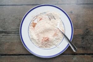 Overhead view of breading mixture for beef schnitzel on a plate with a fork.