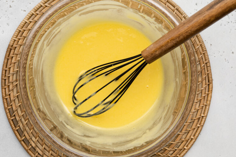 Overhead view of ingredients for keto lemon curd in a large glass bowl with a whisk.