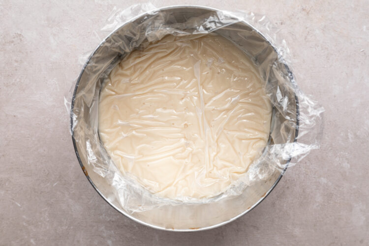 Coconut cream pie filling in large mixing bowl covered with plastic wrap.