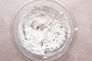 Whipped coconut cream in large glass mixing bowl.