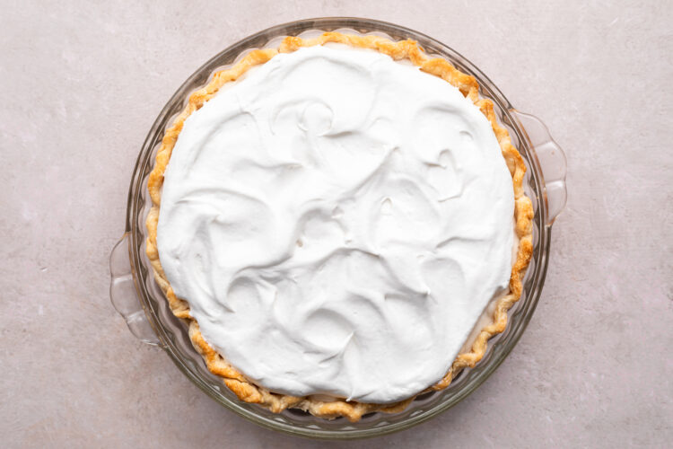 Overhead view of a vegan coconut cream pie topped with coconut whipped cream.