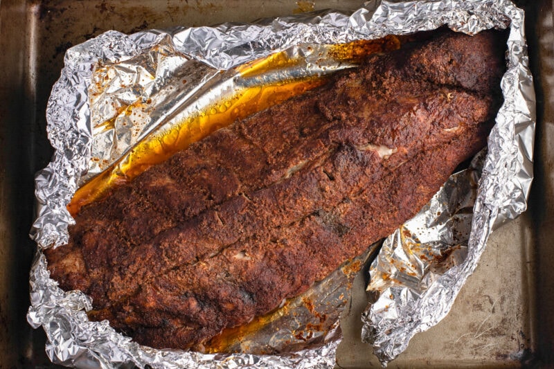 A rack of buffalo ribs on a baking sheet lined with foil.