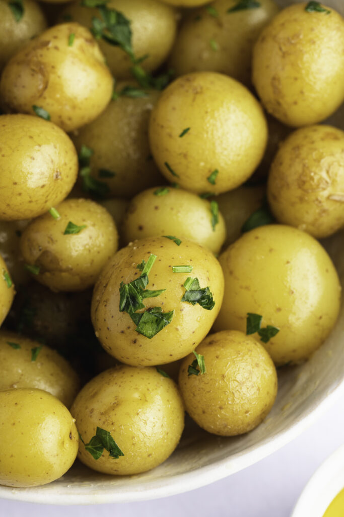 Overhead, close-up view of steamed petite potatoes garnished with freshly chopped parsley.