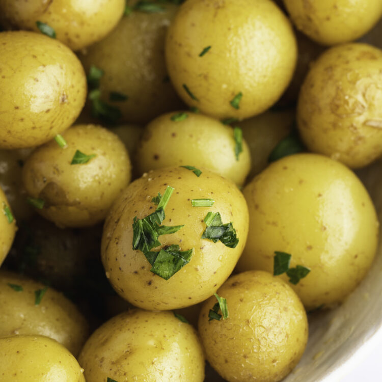 Overhead, close-up view of steamed petite potatoes garnished with freshly chopped parsley.