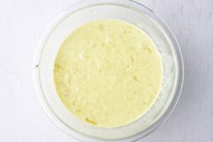 Overhead view of cheese, egg, and cream mixture for a keto breakfast casserole in a glass mixing bowl.
