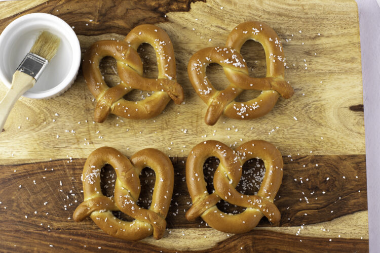 Overhead view of 4 soft twisted frozen pretzels on parchment paper.