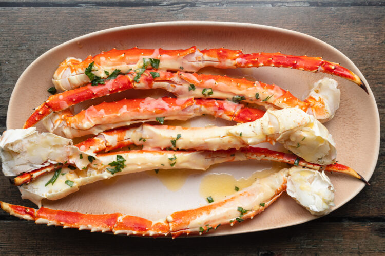 Overhead view of buttered, grilled crab legs on a platter.