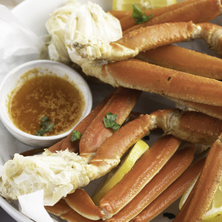 Angled view of a bowl of Instant Pot snow crab legs with a butter sauce.
