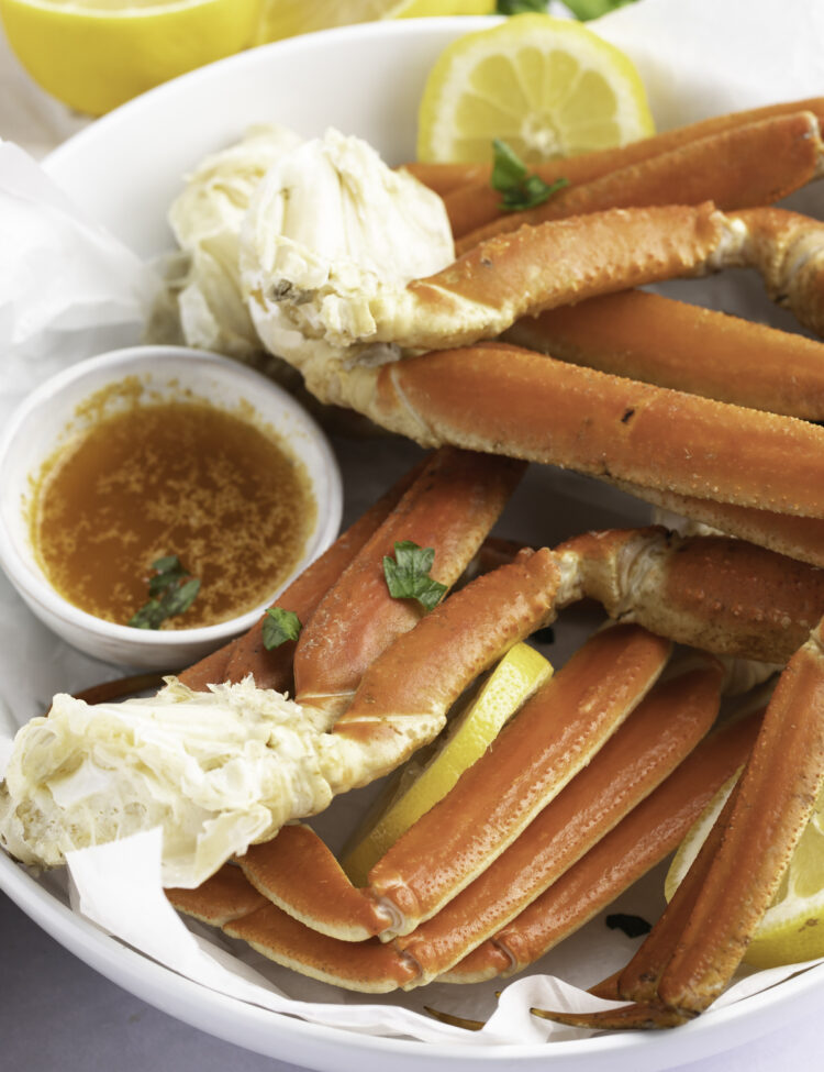 Angled view of a bowl of Instant Pot snow crab legs with a butter sauce.