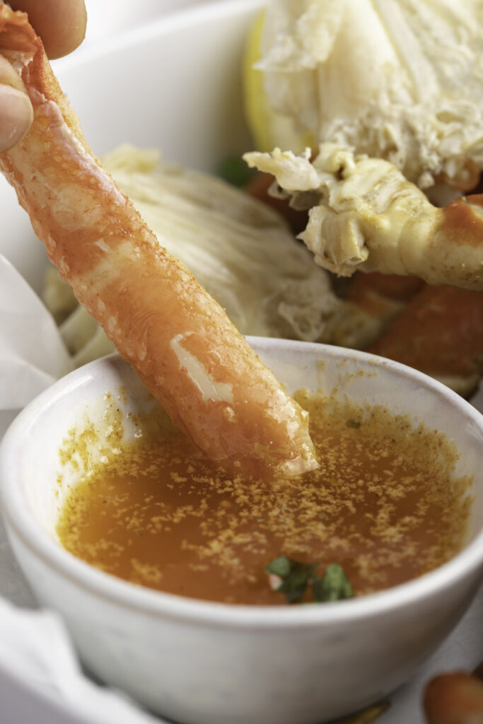 Instant Pot crab legs dipped in a garlic butter sauce.