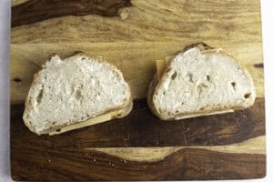 Sourdough sandwiches topped with mayonnaise on a wooden cutting board.