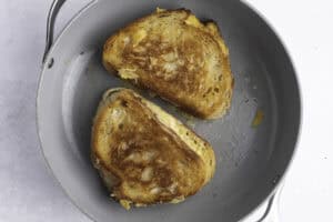 Overhead view of two sourdough grilled cheese sandwiches in a large skillet.