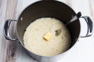 Cooked rice with a pat of butter in a large pot with a fork.