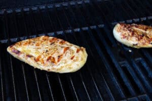 Cooked chicken breasts on grates of grill.