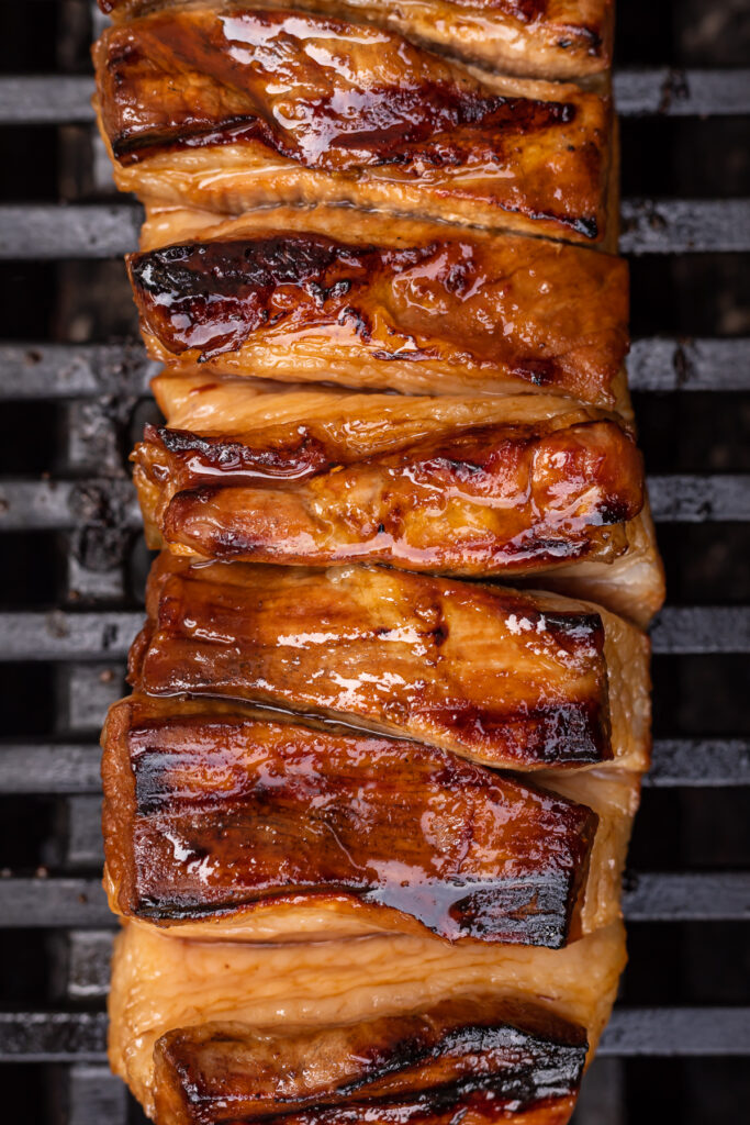 Overhead view of glazed pork belly on a grill.