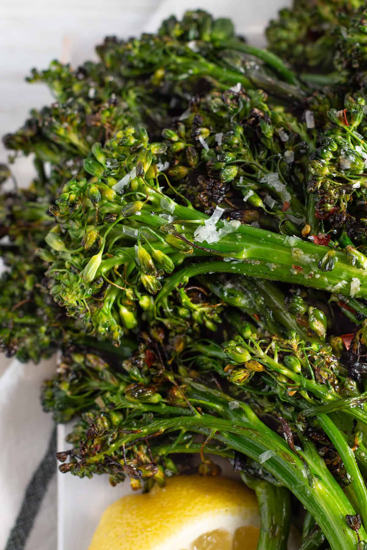 Close-up image of grilled broccolini with parmesan and red chili pepper flakes.
