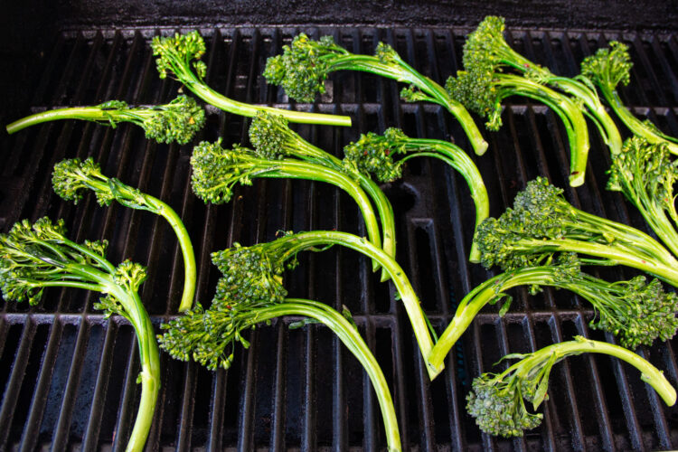 Seasoned broccolini on a grill.