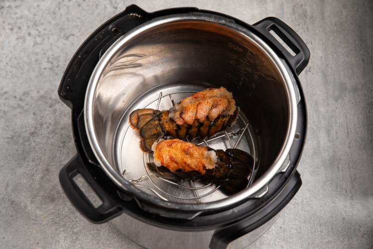 Overhead view of seasoned lobster tails in an Instant Pot on a trivet.