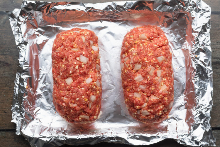 Overhead view of meatloaf mixture divided into 2 equal halves and formed into classic meatloaf shapes.
