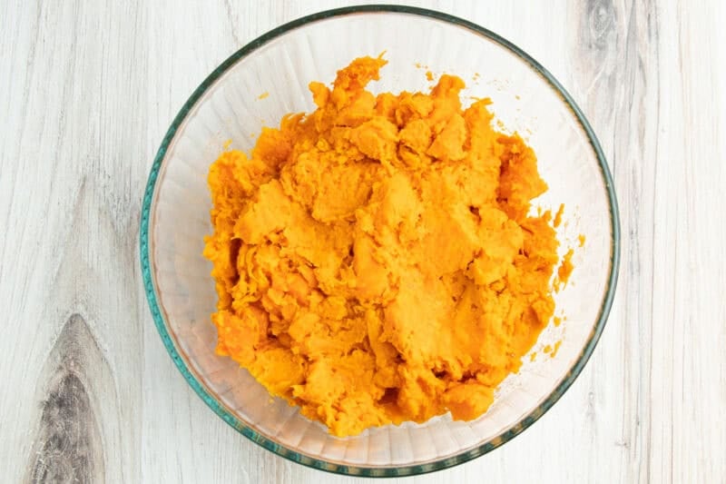 Overhead view of mashed sweet potatoes in a large glass mixing bowl.