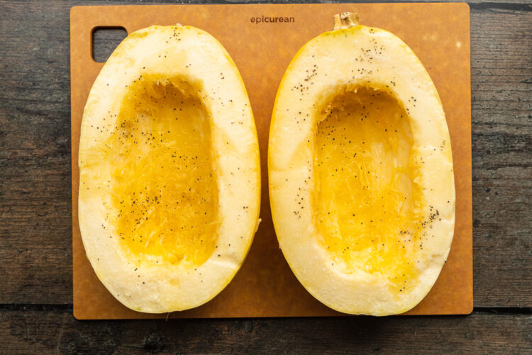 Overhead view of 2 halves of a spaghetti squash on a cutting board.