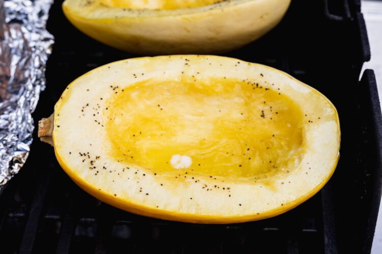 Spaghetti squash halves cut-side up on grill grates over indirect heat.